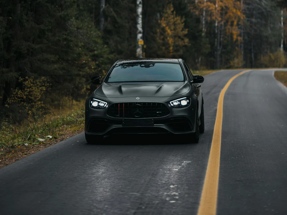 Černý Mercedes AMG jedoucí po lesní silnici